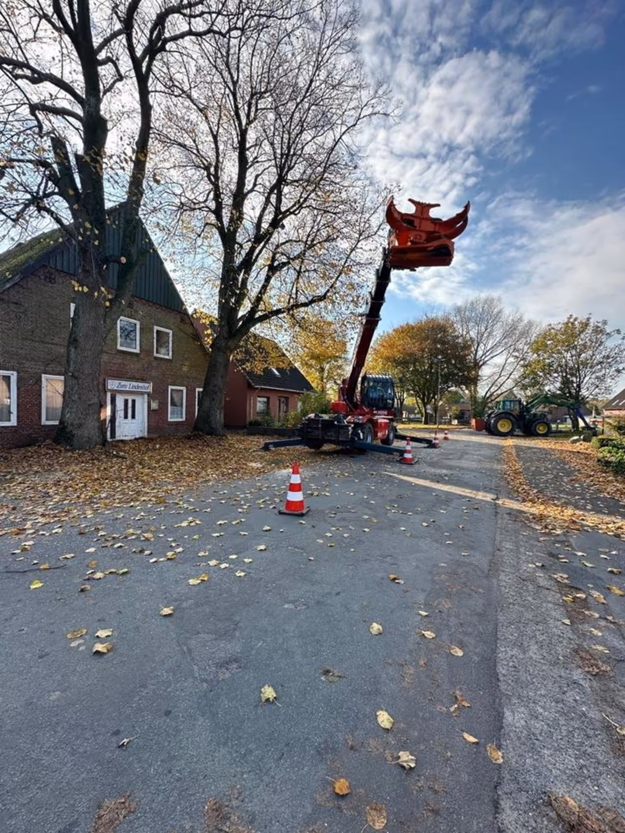 Fällkran an einer Straße neben einem Backsteinhaus im Herbst