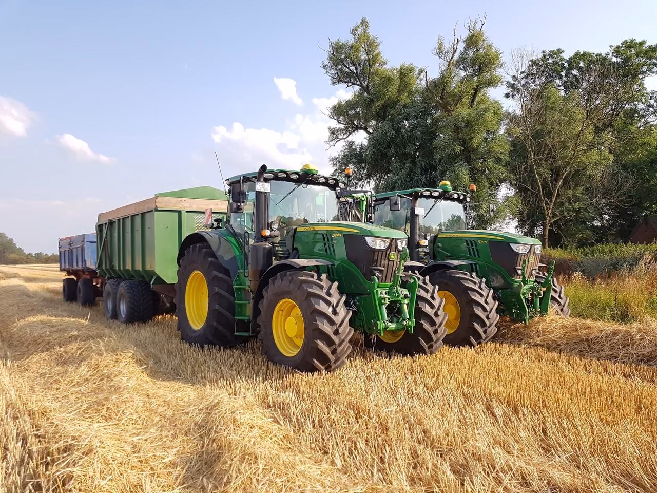 Zwei Schlepper mit Kippanhängern auf einem abgeernteten Feld